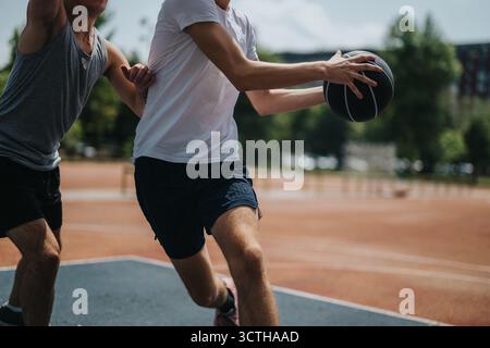 Zwei Männer spielen Basketball auf einem Platz im Freien und zeigen dabei Sportlichkeit, Teamwork und Sommerenergie Stockfoto