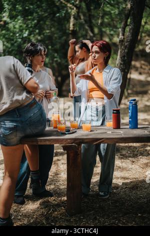 Freunde versammeln sich draußen an einem Holztisch, um Orangensaft und Gespräche zu teilen Stockfoto