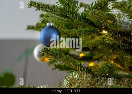 Glänzend blaue Weihnachtskugel hängt an Tannenzweigen. weihnachtsbaumdekoration Stockfoto