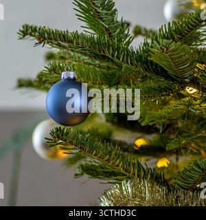 Glänzend blaue Weihnachtskugel hängt an Tannenzweigen. weihnachtsbaumdekoration Stockfoto