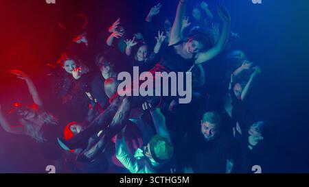 Frau surft über dem jubelnden Publikum der Halloween-Party Stockfoto