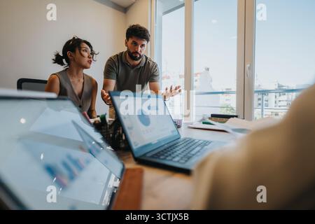 Ein junges Paar berät einen Bankberater über Finanzierungspläne und Darlehensoptionen Stockfoto