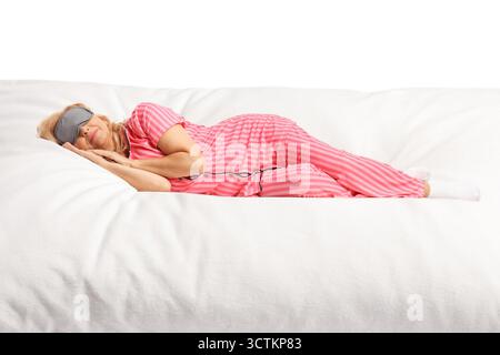 Frau im Pyjama, die eine Maske trägt und auf einer großen weichen Matratze auf weißem Hintergrund schläft Stockfoto