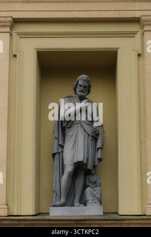 Klassische Marmorstatue eines bärtigen Mannes in einer Toga, stehend in einer Nische an einer historischen Gebäudefassade Stockfoto