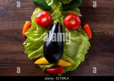 Kreative Gesichtsform aus frischem Gemüse, einschließlich Salat, Auberginen, Tomaten, Gurken und Paprika. Konzept für gesunde Ernährung. Stockfoto