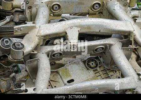 Nahaufnahme von gebrauchten Aluminium-Aufhängungen und -Rahmen mit Schmutz und Verschleiß, gestapelt für Recycling, Schrott oder Wiederverwendung in der Automobilindustrie Stockfoto