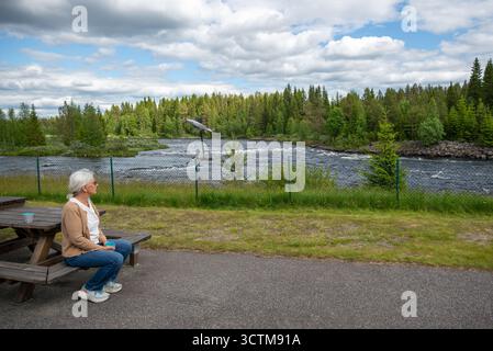Ältere Touristen, die eine Kaffeepause macht und auf den Fluss Vojmån blickt. Stockfoto