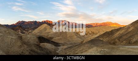 Warme Wüstenlandschaft im 20 Mule Team Canyon bei Sonnenuntergang mit mehrschichtiger Geologie und leuchtenden Bergkämmen Stockfoto