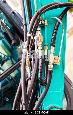 Nahaufnahme komplexer Hydraulikschläuche und Metallfittings an hellblaugrünen Maschinen Stockfoto
