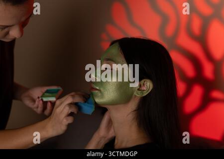 Eine Person hat ihr Gesicht grün bemalt, vielleicht für ein Halloween-Kostüm Stockfoto