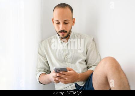 Junger islamischer araber, der zu Hause das Handy benutzt Stockfoto