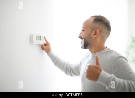 Junge islamische araber benutzen Thermostat zu Hause Stockfoto