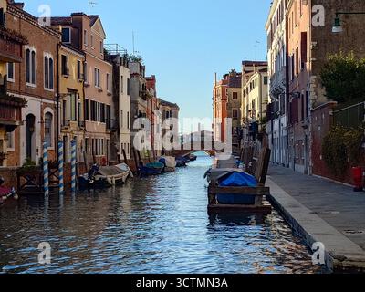 Ein Kanal in Venedig, Italien. Häuser entlang des Kanals, Boote, die an den Häusern verankert sind Stockfoto