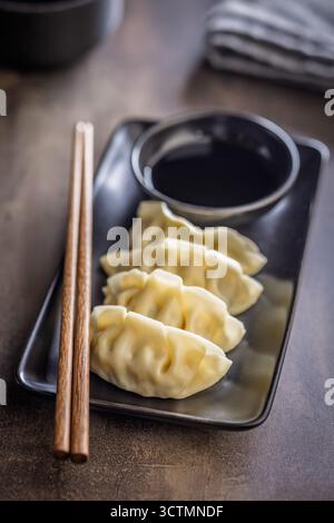 Traditionelle japanische Gyoza-Knödel und Sojasauce auf einem Küchentisch. Stockfoto