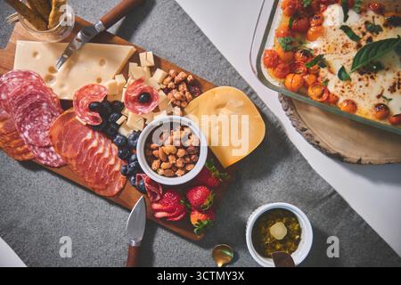 Wurstplatte auf einem grauen Tischset mit verschiedenen Vorspeisen für eine Snackparty Stockfoto