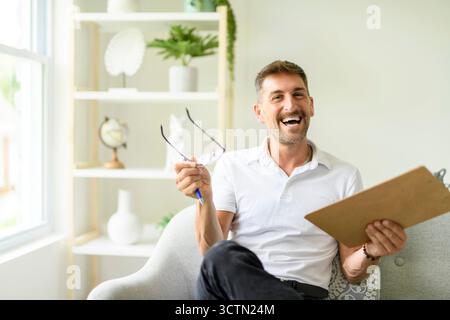 Geschäftsporträt im Büro, selbstbewusst lächelnder Geschäftsmann mittleren Alters, männlicher Psychologe in Brille mit Tablettenpapier Stockfoto