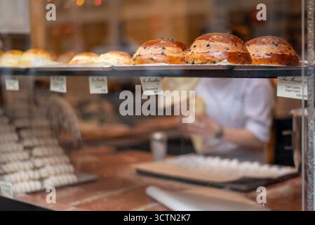 Bäckerei-Ausstellung mit verschiedenen Broten und einem Bäcker im Hintergrund in Prag, Tschechische Republik am 4. Juli 2024 Stockfoto