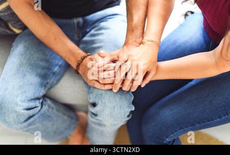 Hand in Hand durch alles. Aufnahme eines unverkennbaren Paares, das die Hände hält, während es zu Hause auf einem Sofa sitzt. Stockfoto
