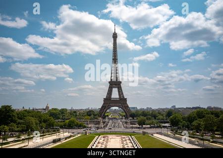 Der Eiffelturm erhebt sich über Paris mit Gärten und einer breiten Avenue unter einem hellen Sommerhimmel. Stockfoto