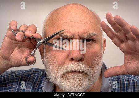 Friseur. Bärtiger Senior-Mann im Friseurladen. Senior Friseur. Bartschnitt im Friseur. Friseurwerbung. Friseur und Haarschnitt. Mann mit Schere Stockfoto