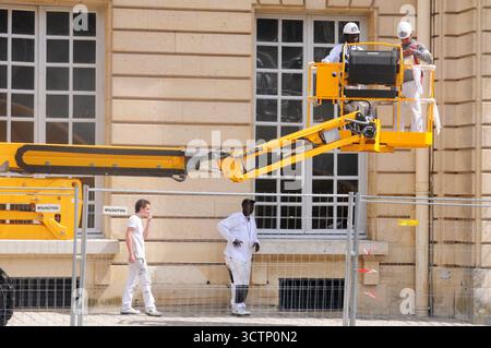 Arbeiter, die eine hydraulische Plattform im Rahmen von Restaurierungs- und Konservierungsarbeiten an der Außenseite des Château de Versailles in Paris, Frankreich, verwenden. Stockfoto