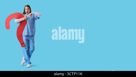 Überraschte Ärztin mit großem Fragezeichen auf hellblauem Hintergrund mit Platz für Text Stockfoto