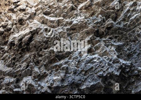 Nahaufnahme einer rauen, zerklüfteten Felswand mit natürlichen Texturen und Tönen Stockfoto