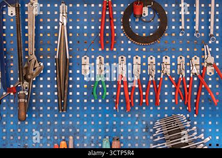 Wandmontiertes Werkzeugset auf Pegboard in der Werkstatt. Alte Handwerkzeuge werden in einer Werkstatteinstellung auf Lochplatte aus Metall angezeigt. Für verwandte Themen verwenden Stockfoto