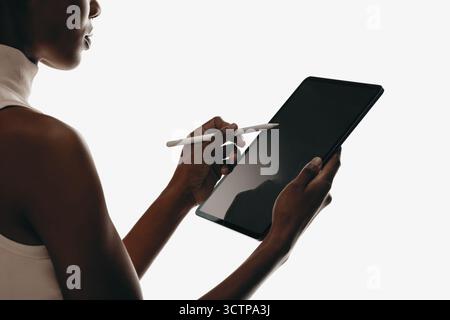 Nahaufnahme einer Frau, die mit einem digitalen Tablet mit einem Stift interagiert, isoliert auf weißem Hintergrund. Perfekt für Gerätemodelle, UI/UX-Design, kreativ Stockfoto