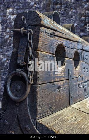 Rostige alte Stämme, Nahaufnahme, historische Foltervorrichtung zur körperlichen Bestrafung mit eisernen Handschellen und einem Loch für die Füße. Stockfoto