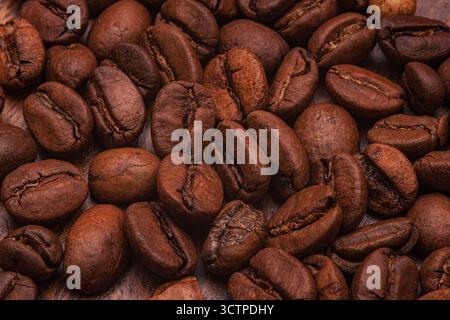Hintergrund geröstete Bio-Kaffeebohnen. Nahaufnahme gerösteter Kaffeebohnen, die einen kräftigen braunen, strukturierten Hintergrund bilden. Zeigen Sie ihre Schärfe Stockfoto