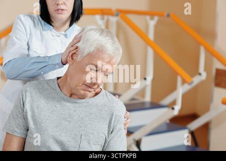 Professionelle Therapeutin mit reifer Kaukasischer Männermassage im Rehabilitationszentrum Stockfoto