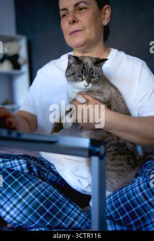 Eine Seniorin arbeitet von zu Hause aus mit einem Haustier, einer Katze Stockfoto