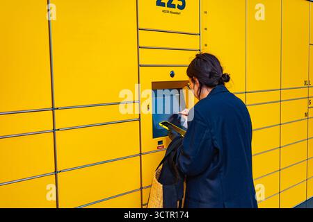 Person, die die DHL Self-Service-Paketstation im Freien nutzt Stockfoto