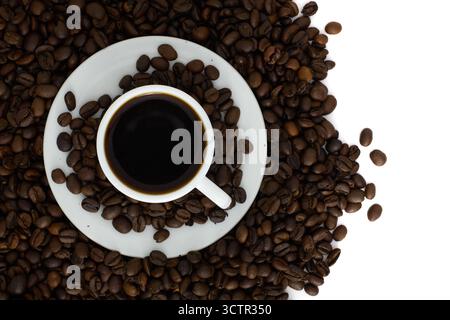 Tasse schwarzen Kaffee umgeben von gerösteten Kaffeebohnen auf weißem Hintergrund. Blick von oben auf ein Konzept für frischen Espresso. Stockfoto