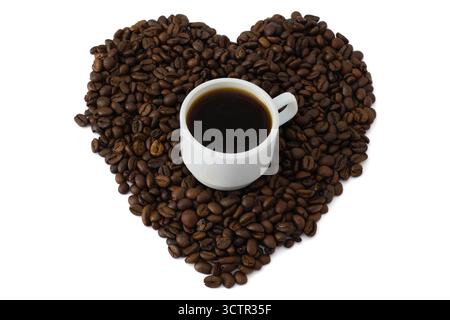 Espresso-Kaffeetasse umgeben von gerösteten Kaffeebohnen in Herzform Stockfoto