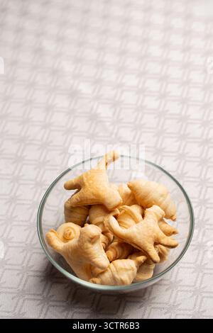 Transparente Schüssel mit Blätterteigcroissants und Keksen in Form von Katzen. Hausgemachte Müslimischung zum trockenen Frühstück, knuspriger festlicher Snack für Kinder und Stockfoto