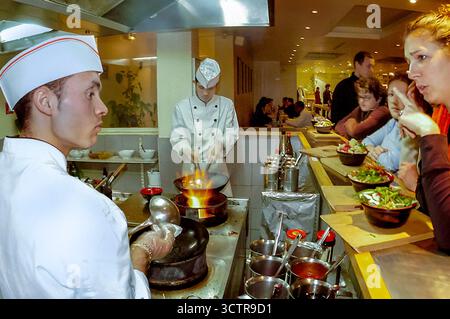 PARIS, Frankreich - männliche Köche bei der Arbeit in offener Küche, chinesisches Innenrestaurant, „Wok“, Theke, im Gespräch mit der Kellnerin Stockfoto