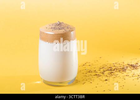 Dalgona-Kaffee mit üppigem Schaum in einem Glas auf gelbem Hintergrund. Trendiges Koreanisches Getränk. Unschärfe und selektiver Fokus Stockfoto