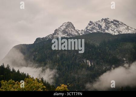 Schönau a. Königssee, Deutschland 08.10.2025: Im Bild: Blick von der Jennerbahn-Bergstation auf die verschneiten Gipfel des Watzmannmassivs mit Watzmannfrau links und Watzmann rechts in Schönau am Königssee. Nebelschwaden ziehen durch den herbstlichen Bergwald und verleihen der Szenerie eine mystische Stimmung Aufnahme vom 8. Oktober 2025. Bayern *** Schönau A Königssee, Deutschland 08 10 2025 im Bild Blick von der Bergstation Jennerbahn auf die schneebedeckten Gipfel des Watzmann-Massivs mit Watzmannfrau links und Watzmann rechts in Schönau am Königssee Weisungen der Nebeldrift t Stockfoto