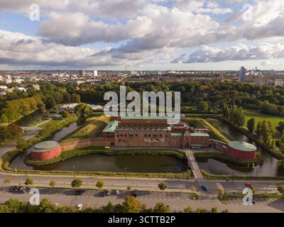 Blick aus der Vogelperspektive auf das Schloss Malmohus, umgeben von reflektierendem Wasser und üppigem Grün unter einem hellen, weiten Himmel, Malmö, Scania County, Schweden. Stockfoto