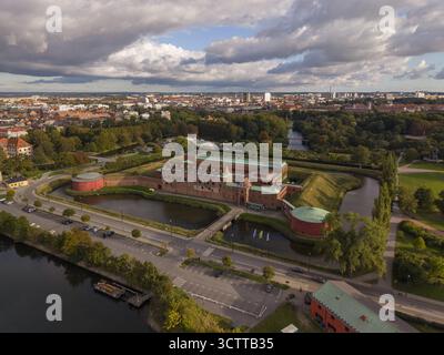 Aus der Vogelperspektive auf die majestätische Burg Malmö, eine Festung umgeben von ruhigen Gewässern, mit der Skyline der Stadt am Horizont, Malmö, Scania County, Schweden. Stockfoto