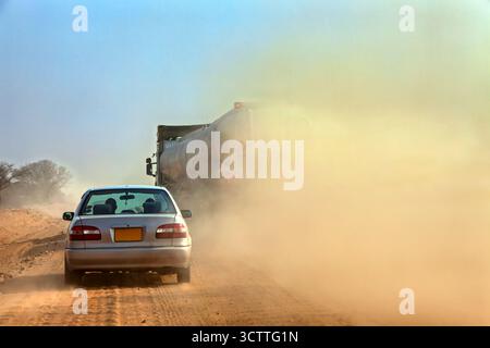 Schotterpiste, staubspuriger Wagen, der einen LKW überholt, afrikanische Straßen in den ländlichen Gebieten Stockfoto