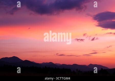 Ruhiger, lebendiger Sonnenuntergang über den Silhouetten der Berge Stockfoto