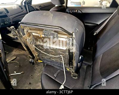 Die Rückseite eines Autositzes, der teilweise entfernt oder zerlegt wurde, wodurch der Metallrahmen und die darunter liegende Verkabelung freigelegt werden, Teil einer Reparatur oder Modifikation Stockfoto
