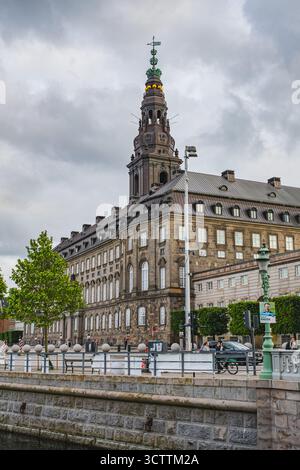 Blick auf das Schloss Christiansborg mit grünen Bäumen und Wasserkanal davor Stockfoto