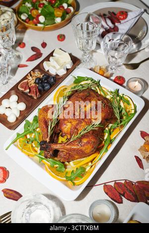 Geröstetes ganzes Huhn garniert mit frischen Kräutern und Zitrusfrüchten auf Thanksgiving-Tisch Stockfoto