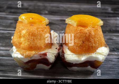Ägyptische Babaz-Torten, aus dem klassischen französischen Rum Baba, knusprigen oder Biskuitschichten, weißer Creme und Früchten wie Ananas, Pfirsich oder gemischt fr Stockfoto