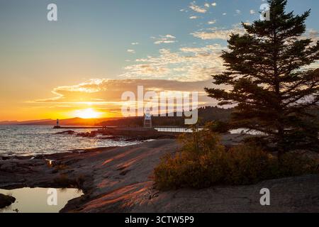 Sonnenuntergang am Artist's Point mit dem Leuchtturm und dem Lake Superior in Grand Marais Minnesota Stockfoto