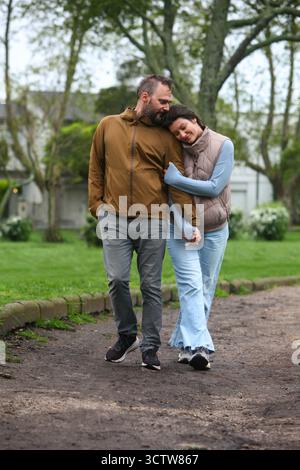 Glückliche Paare mittleren Alters, die im Frühling oder Herbst gemeinsam im Freien spazieren gehen, die Natur genießen und Zeit mit Spaziergängen verbringen und den Park erkunden. Stockfoto